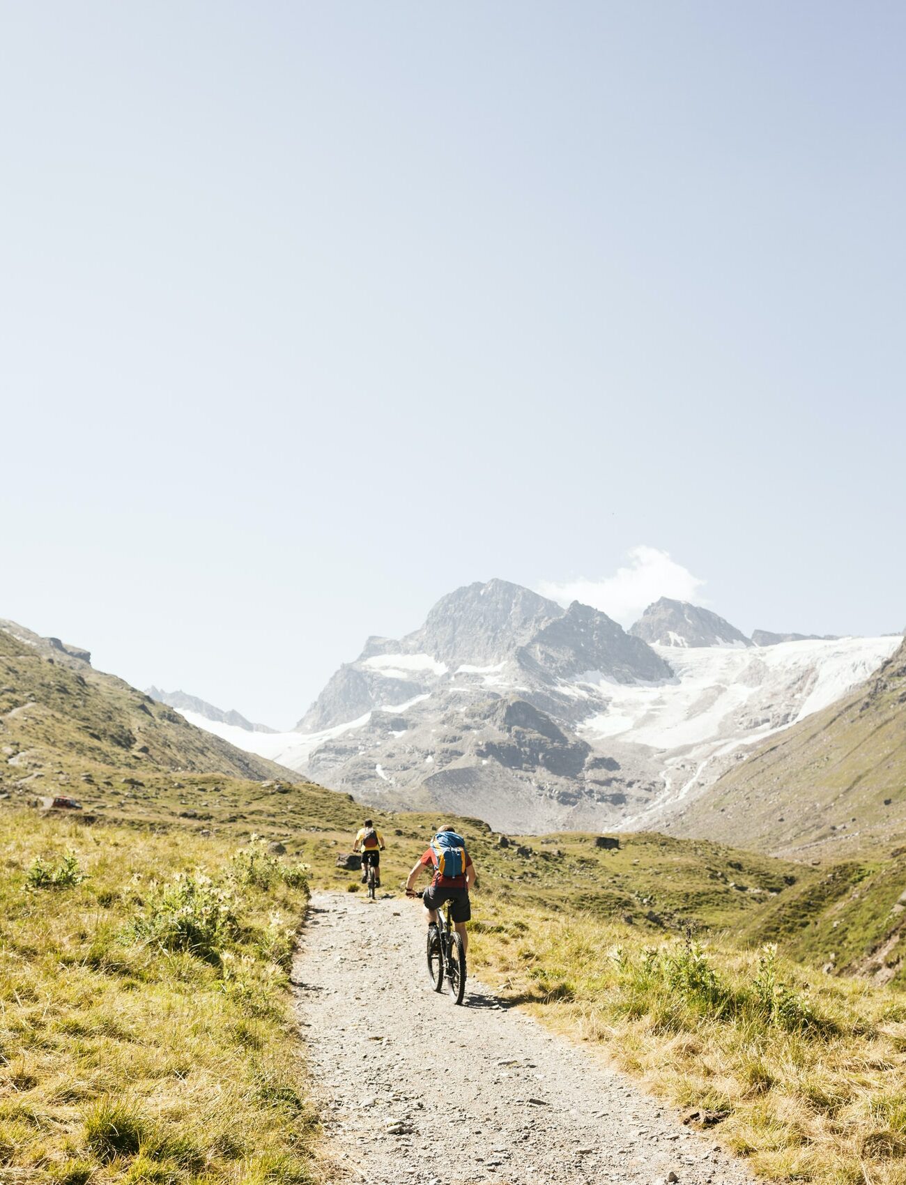 Rear view of cyclists cycling to snow capped mountain range, Partenen, Vorarlberg, Austria